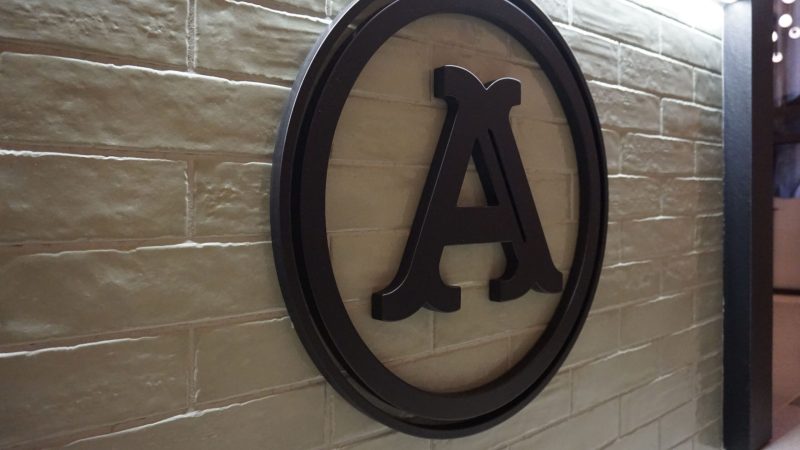 Logo scuro “A” Panificio Anselmo su piastrelle rettangolari verdi