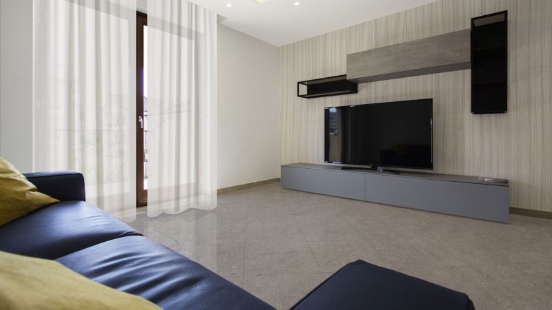 Progetto interior design soggiorno residenziale con divano blu e parete TV